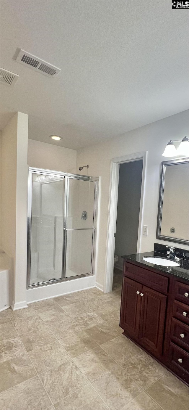 bathroom featuring vanity, a stall shower, toilet, and visible vents