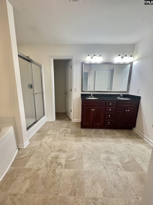 full bathroom with double vanity, a sink, baseboards, and a shower stall