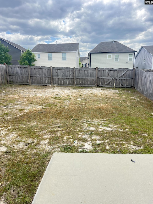 view of yard with a fenced backyard and a gate