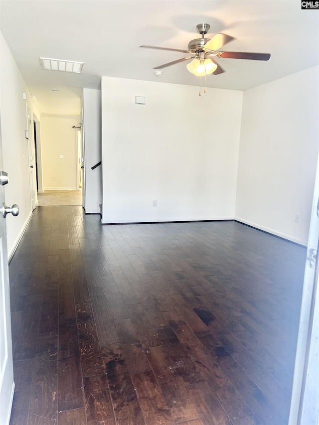 unfurnished room with visible vents, dark wood finished floors, and ceiling fan