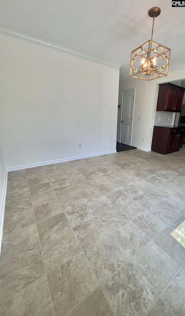 empty room with baseboards, ornamental molding, and a notable chandelier