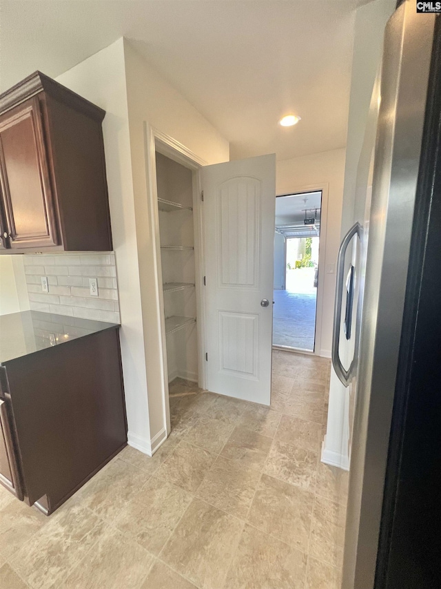 kitchen featuring dark countertops, tasteful backsplash, baseboards, stainless steel fridge, and recessed lighting