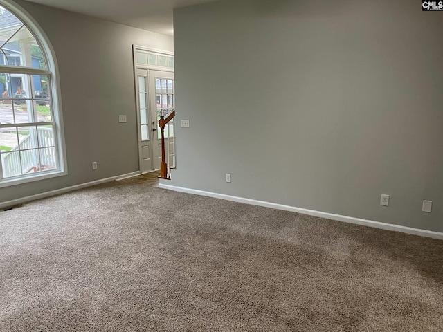 empty room with baseboards, plenty of natural light, and dark colored carpet