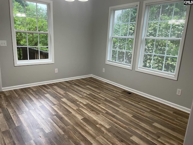 spare room with dark wood-style flooring, baseboards, and visible vents