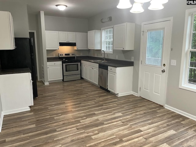 kitchen featuring dark countertops, a sink, dark wood-style floors, under cabinet range hood, and stainless steel appliances