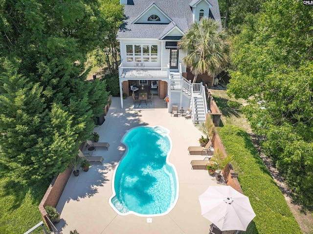 rear view of property featuring a patio, stairway, and an outdoor pool