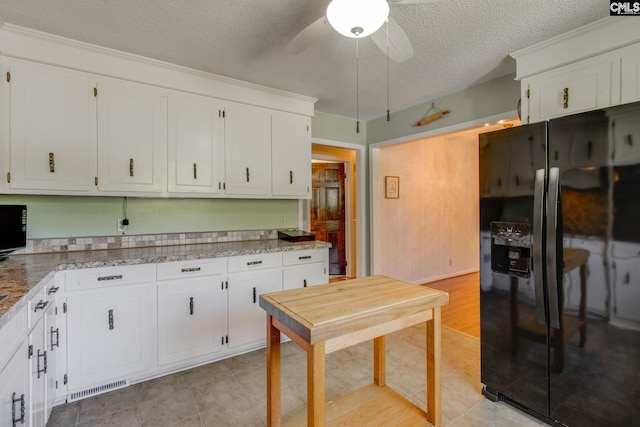 kitchen with white cabinets, a textured ceiling, ceiling fan, and black refrigerator with ice dispenser