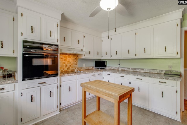 kitchen with a textured ceiling, under cabinet range hood, white cabinets, a ceiling fan, and black appliances