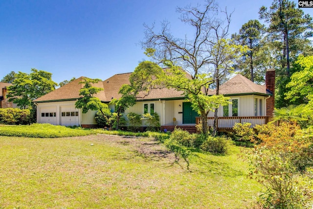 ranch-style home featuring board and batten siding, an attached garage, a chimney, and a front yard