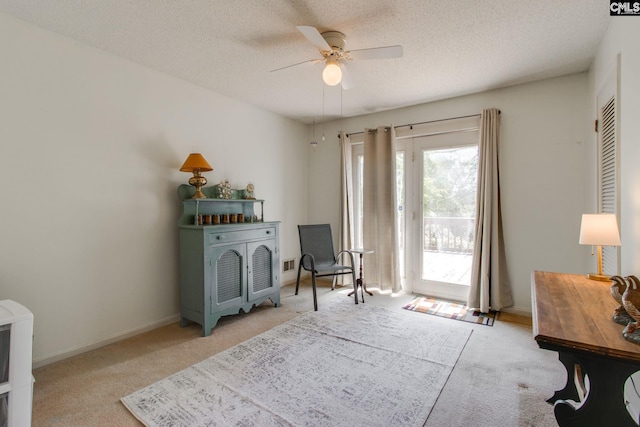 living area featuring carpet flooring, a ceiling fan, a textured ceiling, and plenty of natural light