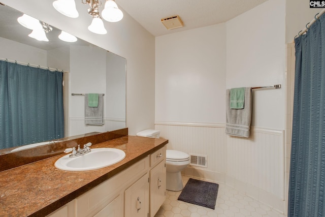 full bath featuring visible vents, tile patterned flooring, a wainscoted wall, vanity, and toilet