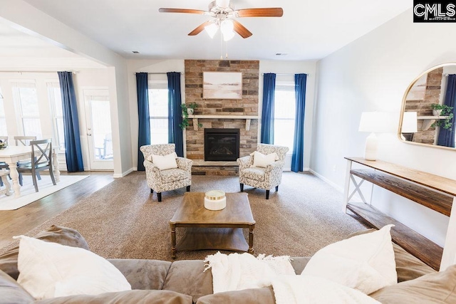 living area featuring baseboards, ceiling fan, and a fireplace