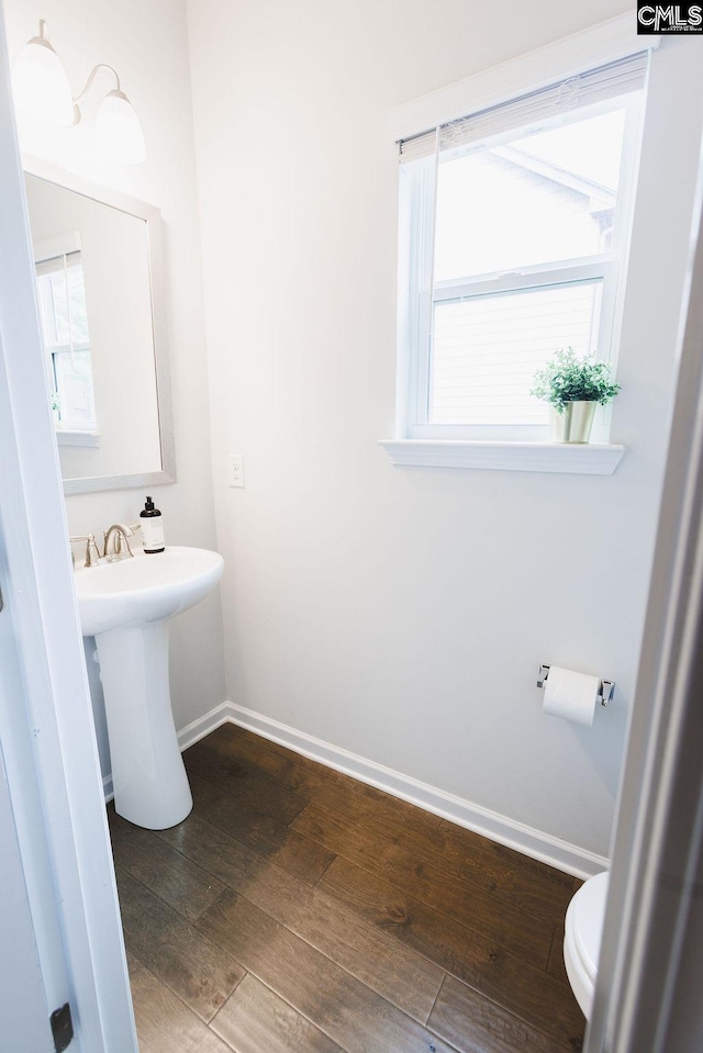 half bath featuring toilet, baseboards, and wood finished floors