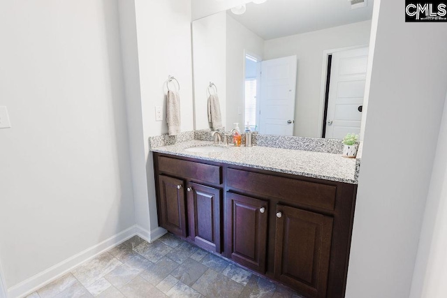 bathroom with baseboards, visible vents, stone finish floor, and vanity
