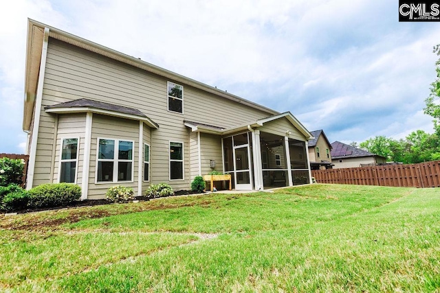 rear view of house featuring a sunroom, a lawn, and fence