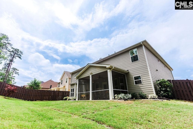 rear view of property featuring a sunroom, a ceiling fan, a fenced backyard, and a yard