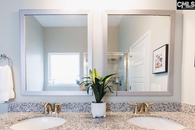 full bath with a sink, a stall shower, and double vanity