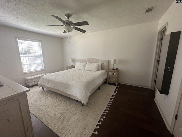 bedroom featuring a textured ceiling, ceiling fan, wood finished floors, and visible vents