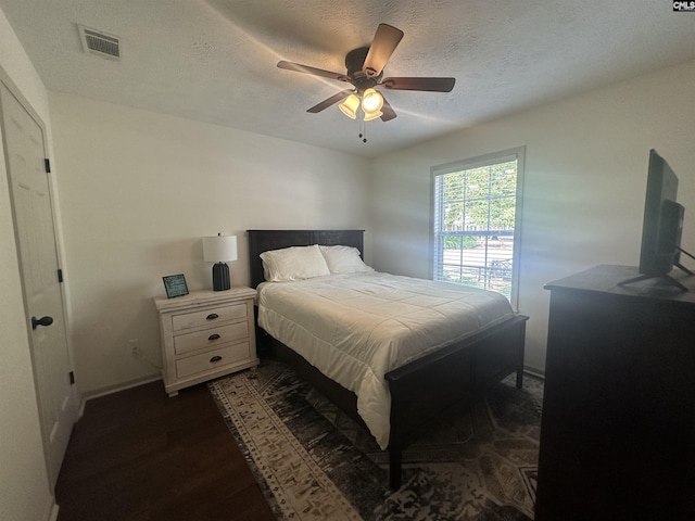 bedroom featuring visible vents, dark wood-style flooring, baseboards, a textured ceiling, and a ceiling fan