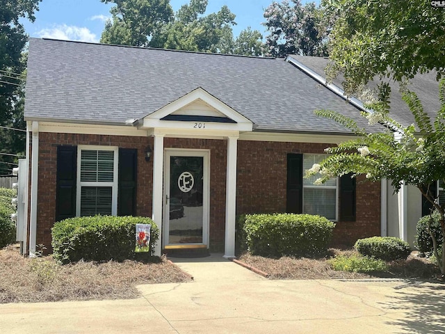 view of front of house featuring brick siding and a shingled roof