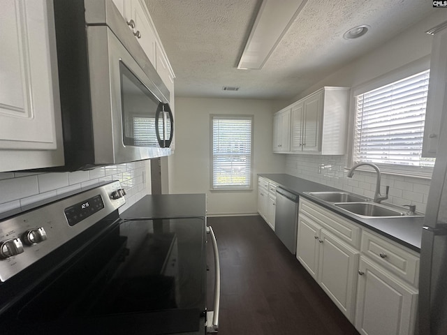 kitchen with a sink, a textured ceiling, appliances with stainless steel finishes, and white cabinets