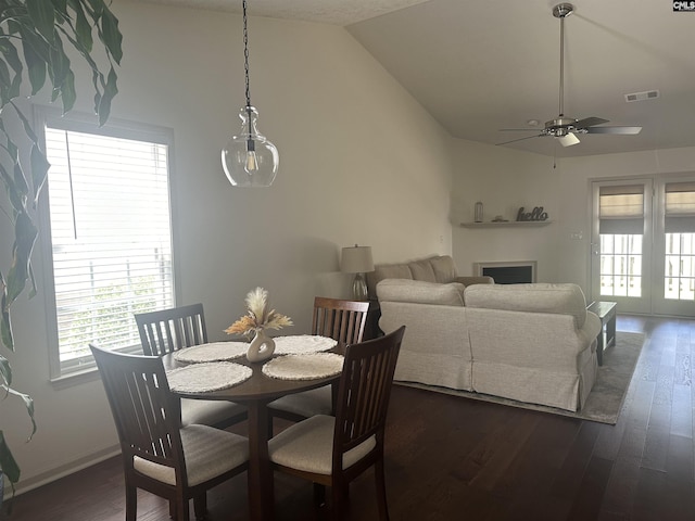 dining room with visible vents, dark wood-style flooring, a fireplace, ceiling fan, and vaulted ceiling