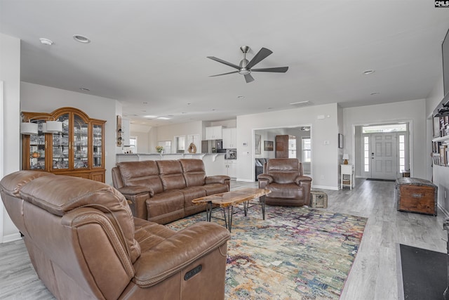 living area with light wood-type flooring, baseboards, and ceiling fan