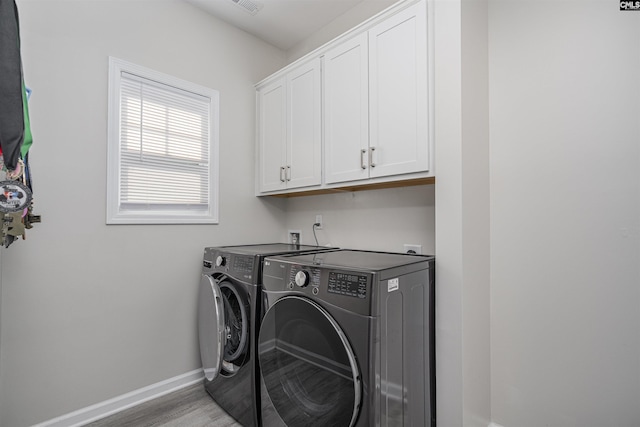washroom with visible vents, washing machine and dryer, baseboards, light wood-style floors, and cabinet space