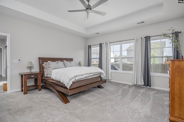 carpeted bedroom with a raised ceiling, baseboards, ceiling fan, and visible vents