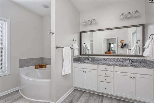 full bathroom featuring baseboards, a sink, and wood finished floors