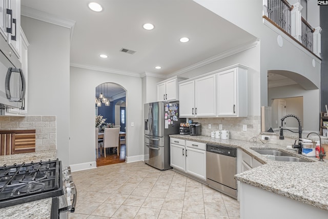 kitchen with crown molding, appliances with stainless steel finishes, a sink, arched walkways, and visible vents