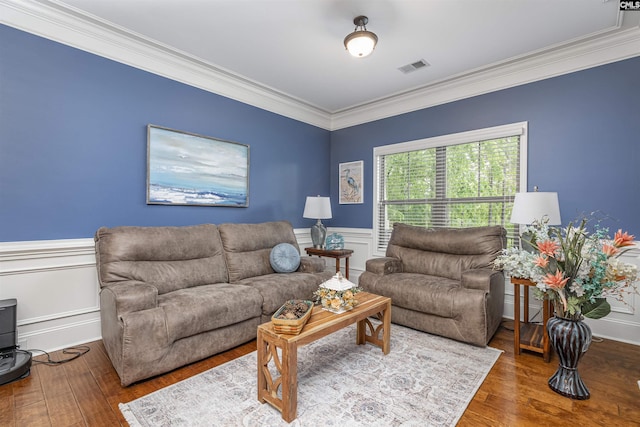 living room with visible vents, ornamental molding, wainscoting, and wood finished floors