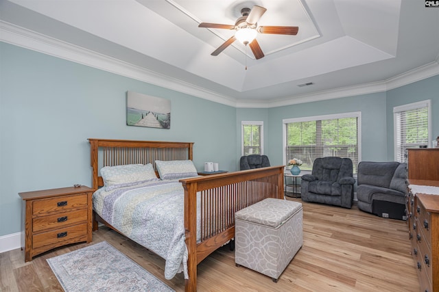 bedroom with light wood finished floors, a raised ceiling, a ceiling fan, visible vents, and ornamental molding
