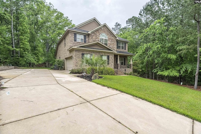 craftsman-style house with stone siding, a front yard, brick siding, an attached garage, and driveway