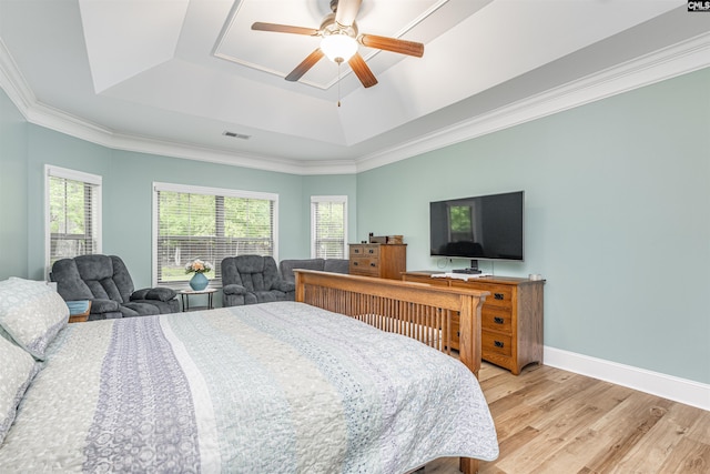 bedroom with a raised ceiling, a ceiling fan, baseboards, wood finished floors, and visible vents