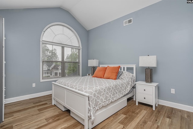 bedroom featuring baseboards, visible vents, vaulted ceiling, and light wood-style floors