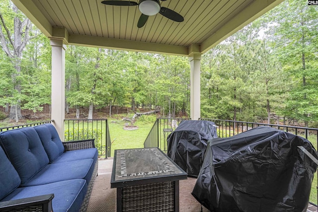 view of patio / terrace featuring an outdoor living space with a fire pit, area for grilling, a deck, a forest view, and a ceiling fan