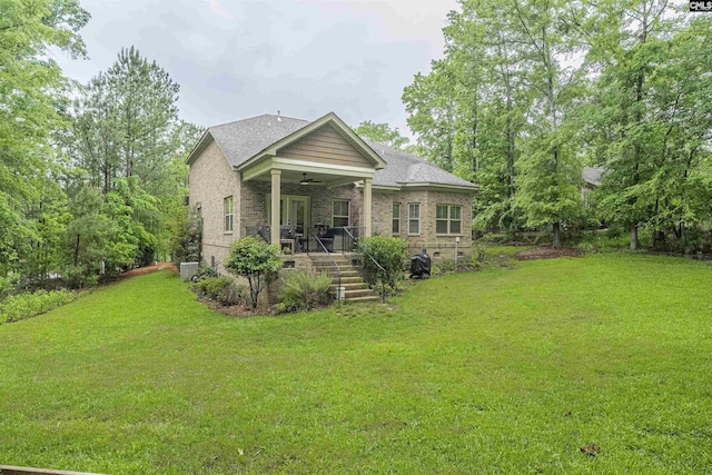 rear view of property featuring a yard, brick siding, ceiling fan, and a porch