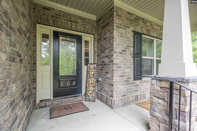 entrance to property featuring covered porch and brick siding