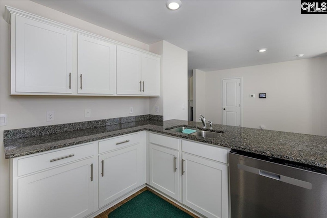 kitchen featuring a sink, dark stone counters, stainless steel dishwasher, and white cabinetry