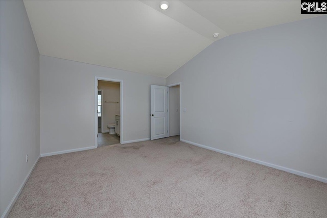 unfurnished bedroom featuring baseboards, carpet, ensuite bathroom, and lofted ceiling