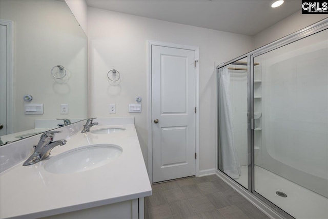 bathroom with double vanity, a sink, and a stall shower