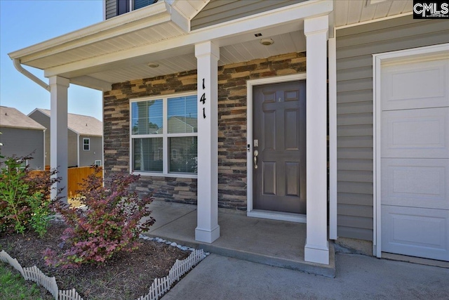 view of exterior entry with covered porch and stone siding