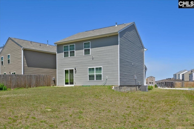 rear view of house featuring fence, central AC unit, and a lawn