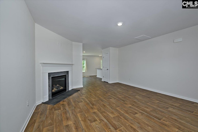 unfurnished living room featuring a glass covered fireplace, baseboards, recessed lighting, and dark wood finished floors