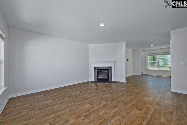 unfurnished living room with recessed lighting, a fireplace with flush hearth, baseboards, and wood finished floors