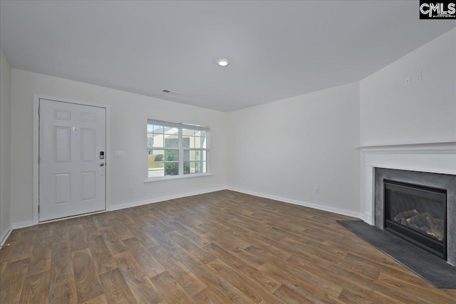 unfurnished living room with visible vents, baseboards, wood finished floors, and a fireplace