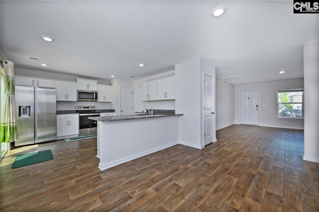 kitchen featuring white cabinets, a peninsula, dark wood-style floors, and stainless steel appliances