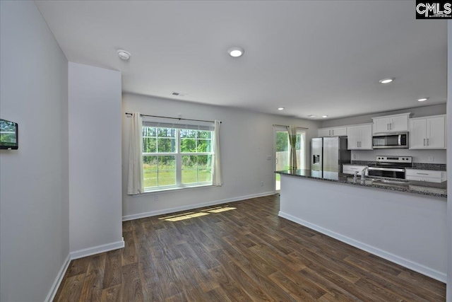kitchen with baseboards, white cabinets, stainless steel appliances, and dark wood-type flooring