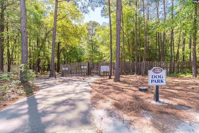 view of community featuring fence, a gate, and a forest view